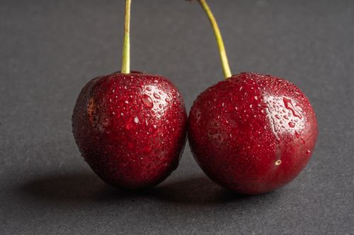Free A close-up image showcasing two fresh cherries covered in water droplets, highlighting their juicy appeal. Stock Photo