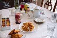 A beautifully arranged breakfast table with croissants, macarons, and tea set, perfect for a cozy morning.