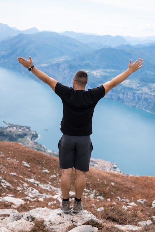 Back View of a Man on a Mountain Raising His Hands