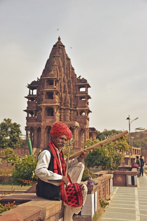 Free A musician in traditional attire playing an instrument in front of an ancient temple. Stock Photo