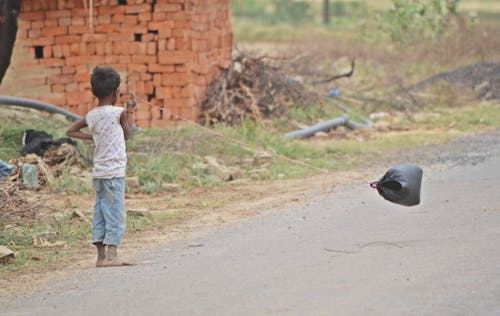 A Young Boy Standing Barefeet on the Dirt Road