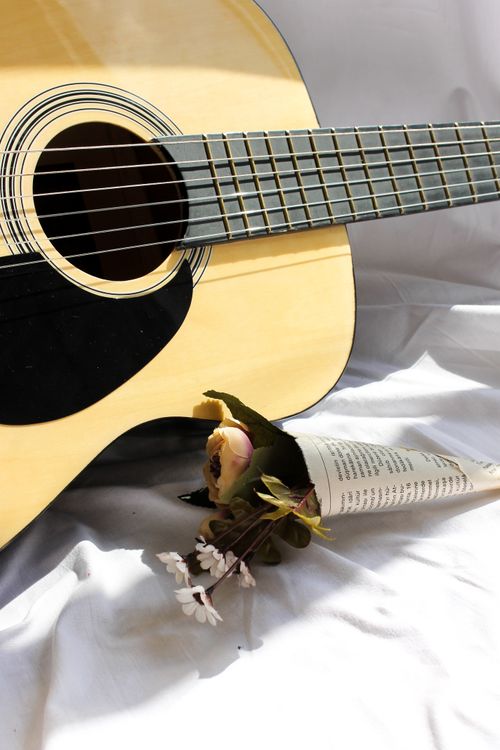 Free A still life of an acoustic guitar paired with a delicate floral bouquet, evoking a sense of harmony. Stock Photo