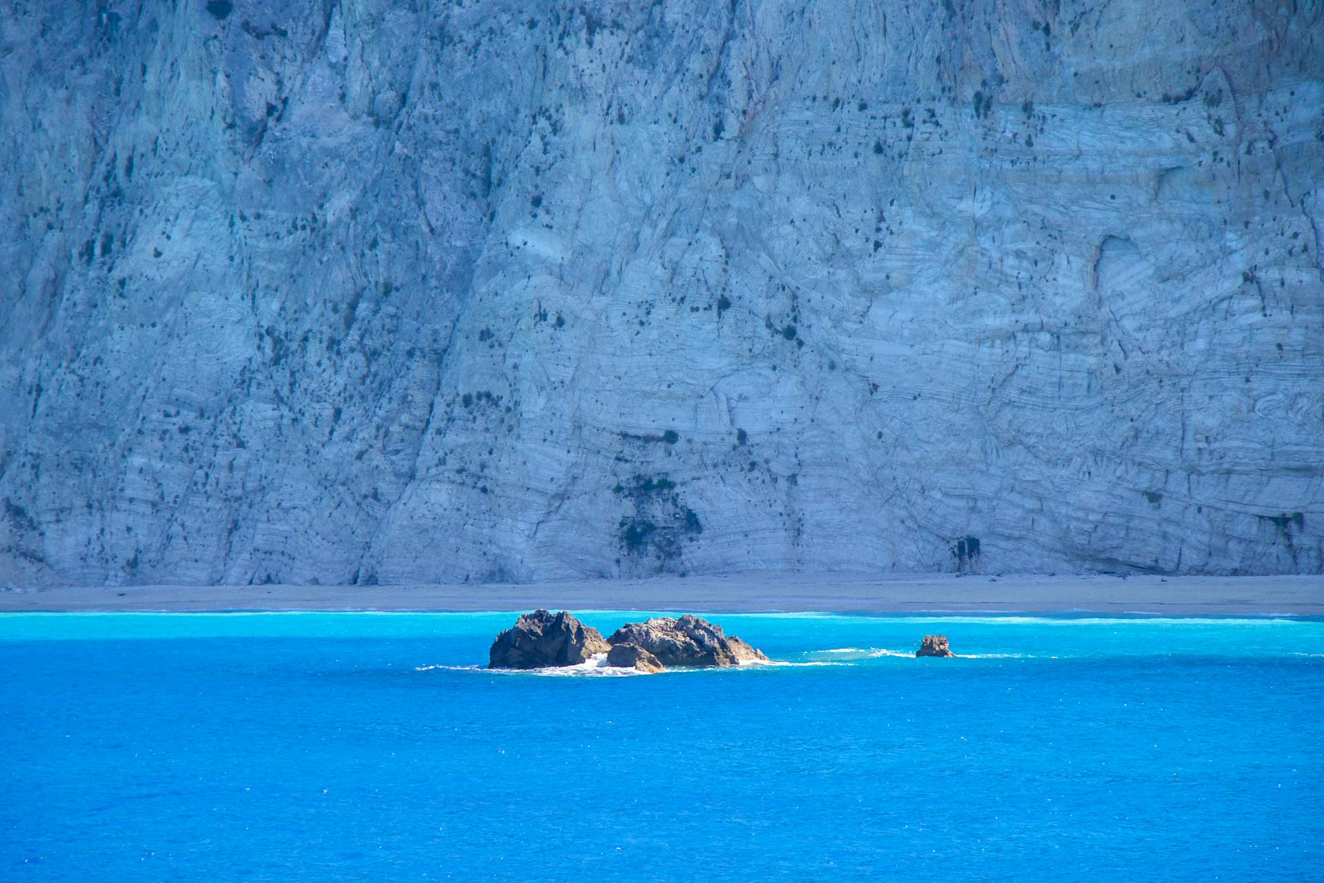 Breathtaking view of azure waters and rocky cliffs along the Aegean coastline in Greece.