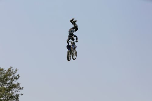 Free Daring motocross stunt rider performing aerial tricks on motorcycle against clear sky. Stock Photo