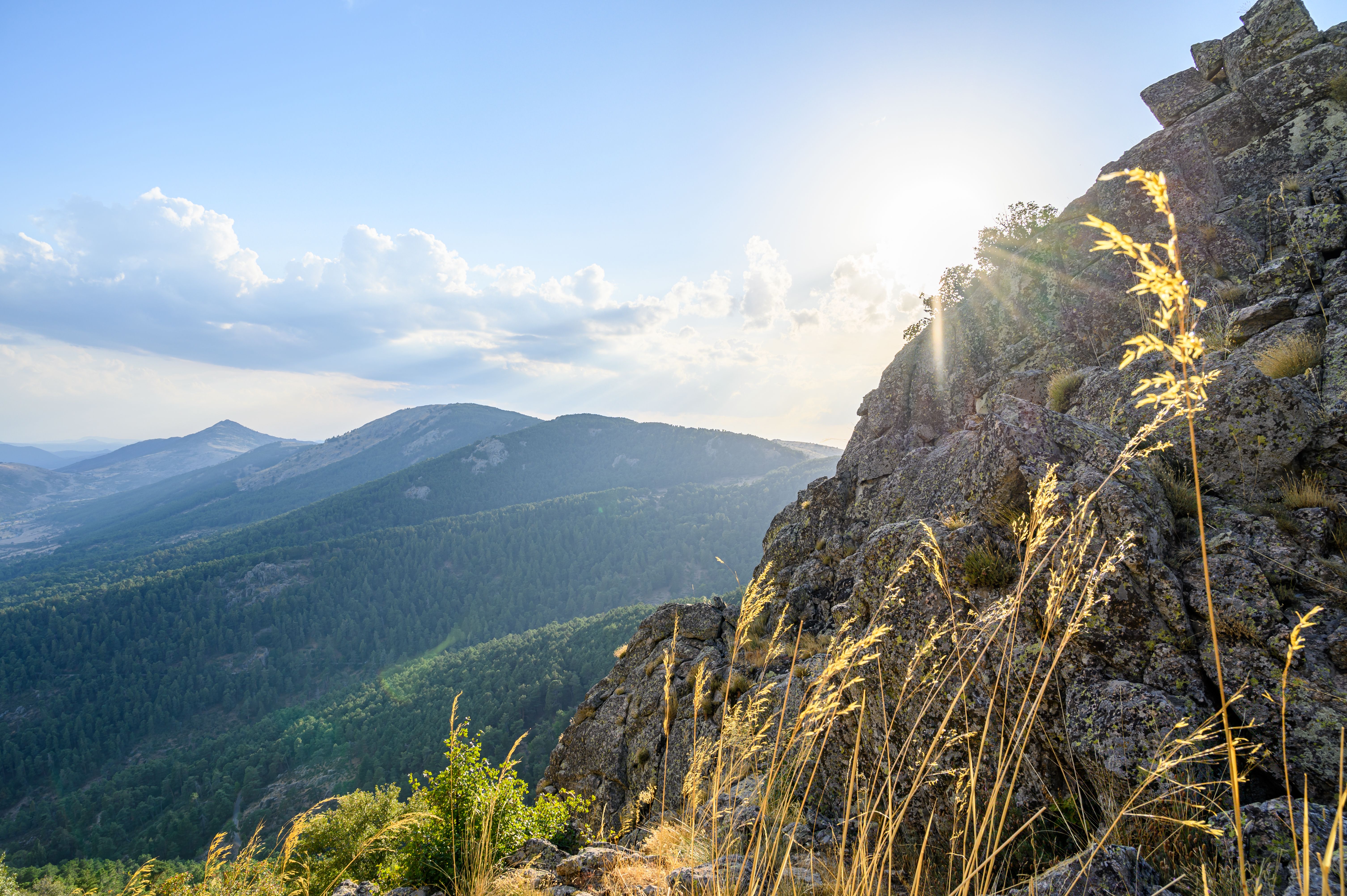 A Rock Formation and Mountains Under the Blue Sky and White Clouds ...