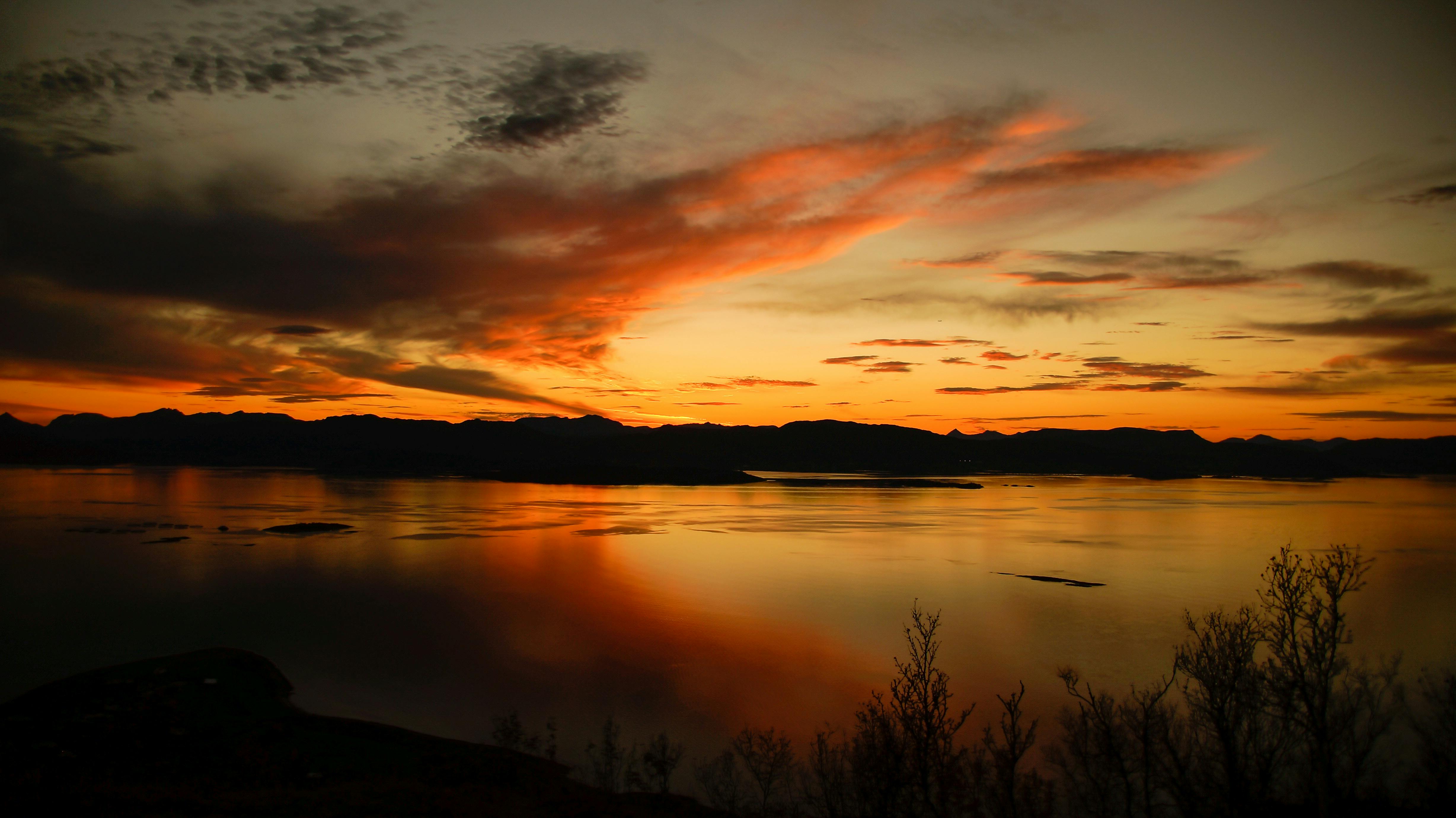 Captivating sunset with dramatic skies reflecting over a serene Norwegian lake.