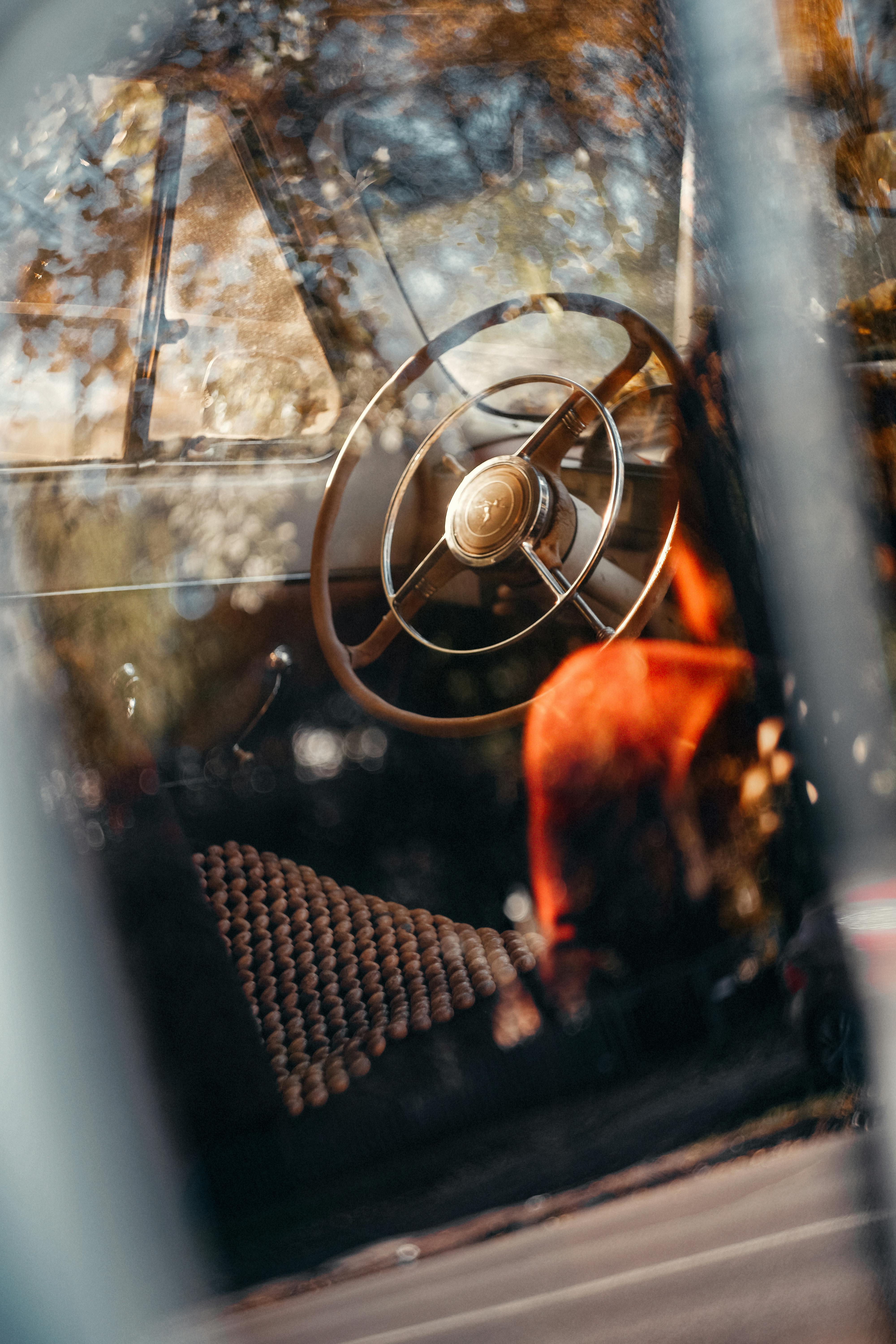 Close-up of vintage car interior showcasing a classic steering wheel and reflections.