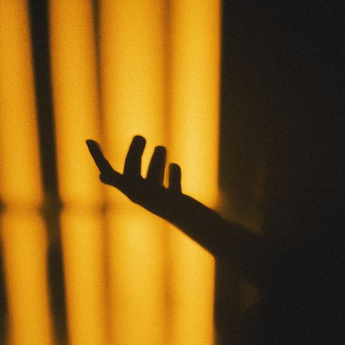 Free Artistic hand silhouette on a vibrant yellow backdrop creates a dramatic visual. Stock Photo