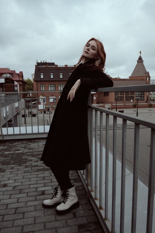 Free A fashionable woman with colored hair poses outdoors against a cityscape backdrop. Stock Photo
