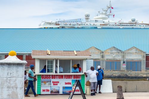 Free People gathering at a glass bottom ferry booth by the waterfront with a large ship in the background. Stock Photo