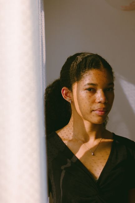Elegant portrait of a woman with light reflecting on her face, highlighting freckles.