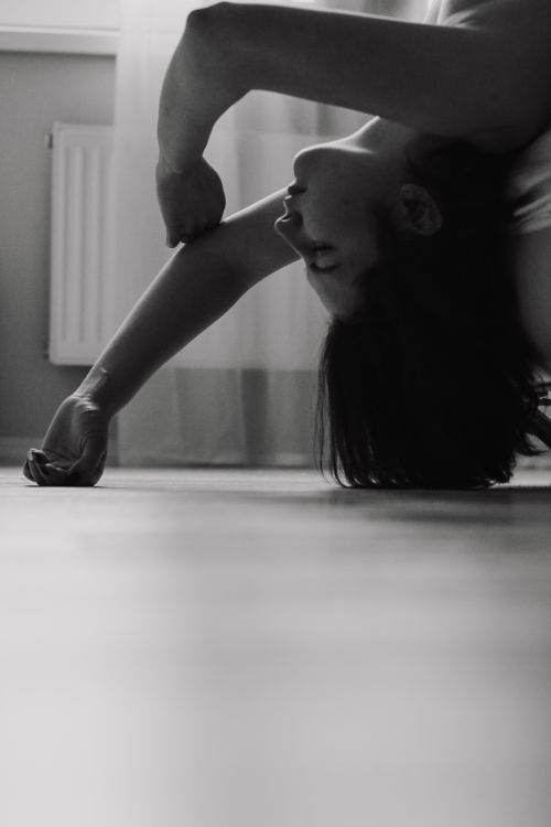 Free A monochrome image capturing a woman in a unique yoga pose indoors, showcasing flexibility. Stock Photo