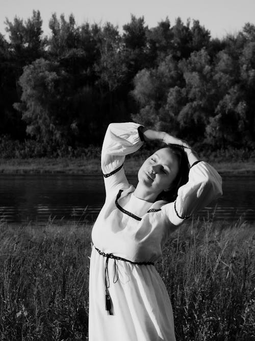Free Grayscale Photo of a Woman in Dress while Standing on a Grass Field Stock Photo