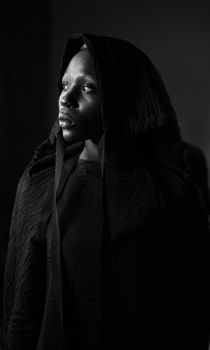 Elegant black and white portrait of a woman in a hood, exuding a moody and dramatic atmosphere.