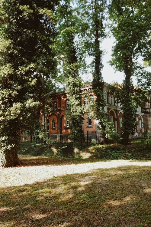 Free Charming historic brick mansion nestled amidst lush trees and a sunny yard. Stock Photo