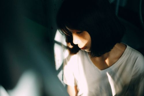 Free Moody portrait of a woman in soft shadow lighting, conveying deep thought. Stock Photo