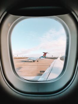 Airplane window view capturing nearby jet on tarmac, perfect for travel themes.