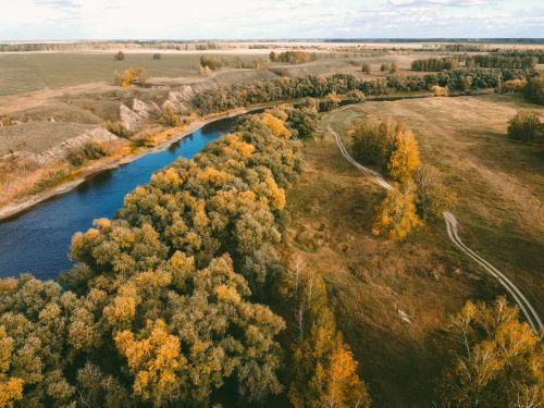 Free Aerial shot of a picturesque countryside landscape with a winding river and autumn foliage. Stock Photo