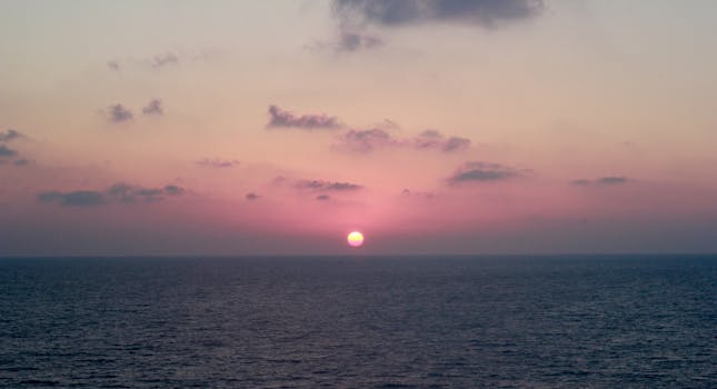 海面上，日落宁静，天空淡雅而充满活力，水域一片平静