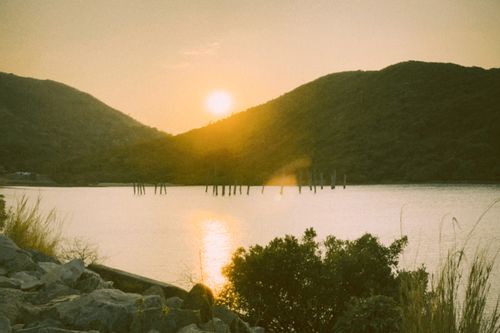 Free A tranquil sunset over a serene lake in Hong Kong, with green mountains in the background. Stock Photo