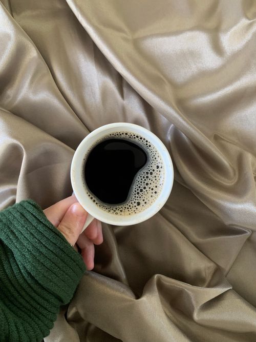 Free Top view of a coffee cup on luxury silk with a cozy sweater, perfect start to the day. Stock Photo