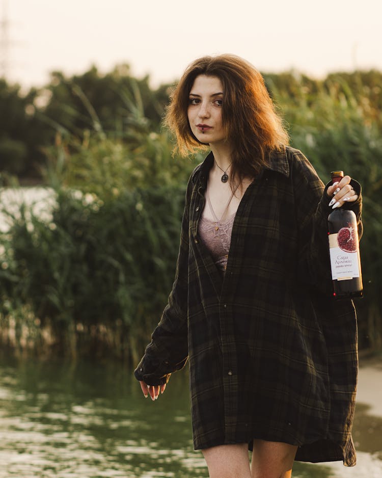 A Woman In A Plaid Shirt Holding A Bottle Of Wine