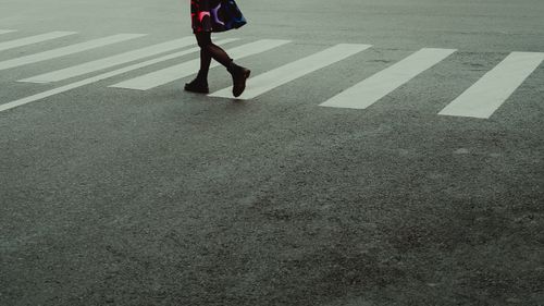 Free A person in colorful attire crosses a pedestrian lane, showcasing city street fashion. Stock Photo