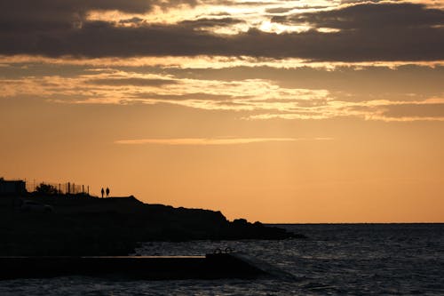 Seashore at Sunset With Silhouettes of Two People Standing in the Distant Background