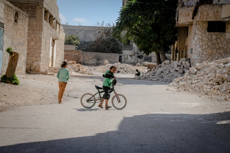 Kid With Bicycle In Demolished City