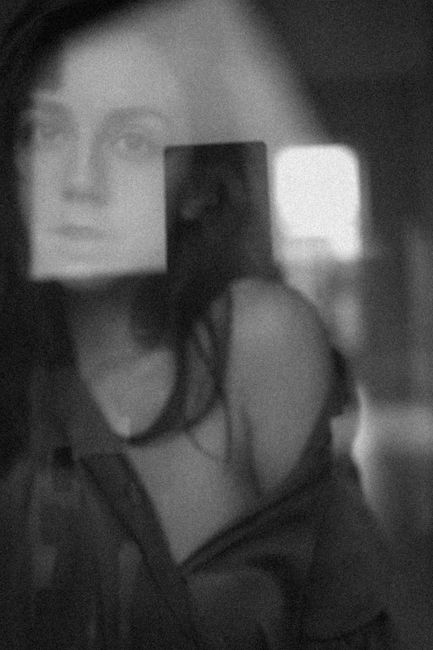Expressive black and white portrait showcasing a woman's reflection through glass.