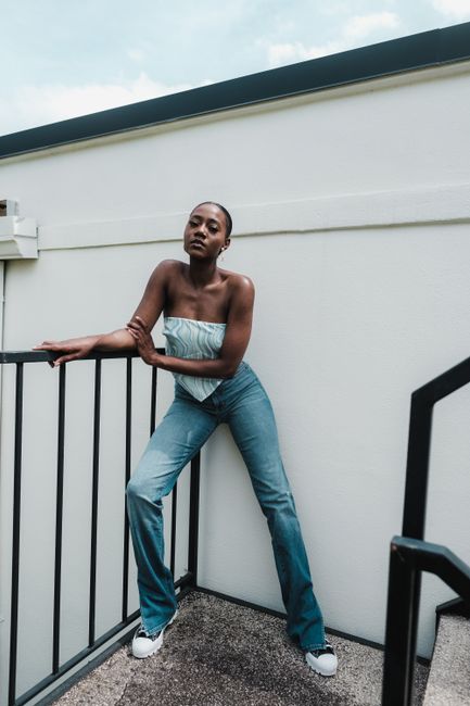 Confident woman in jeans posing on outdoor stairs in Orlando, embracing modern fashion style.