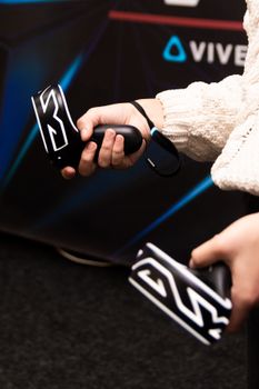 Person holding virtual reality game controllers, focusing on technology and interaction.