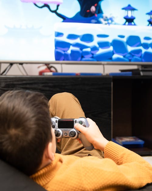 Boy Holding a Gamepad While Playing a Video Game