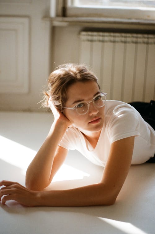 Young woman wearing eyeglasses and laying down on floor