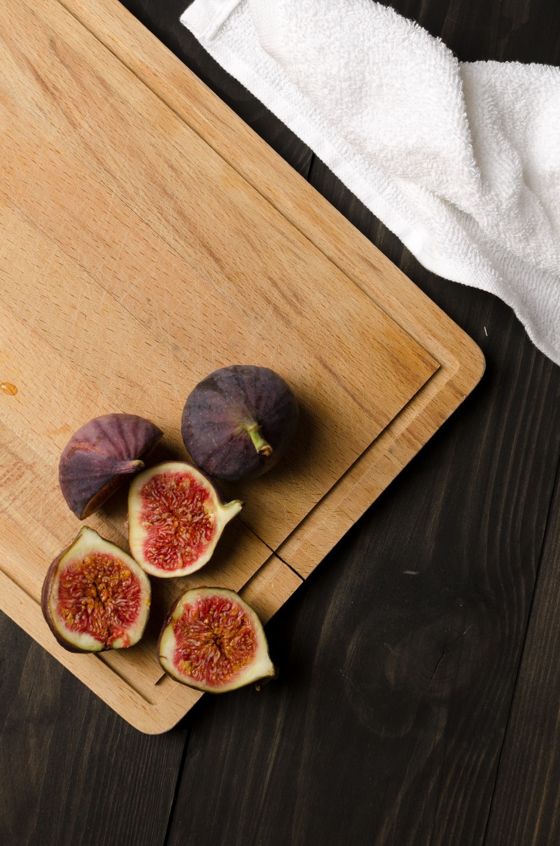 Beechwood cutting board with juice groove holding fresh halved figs