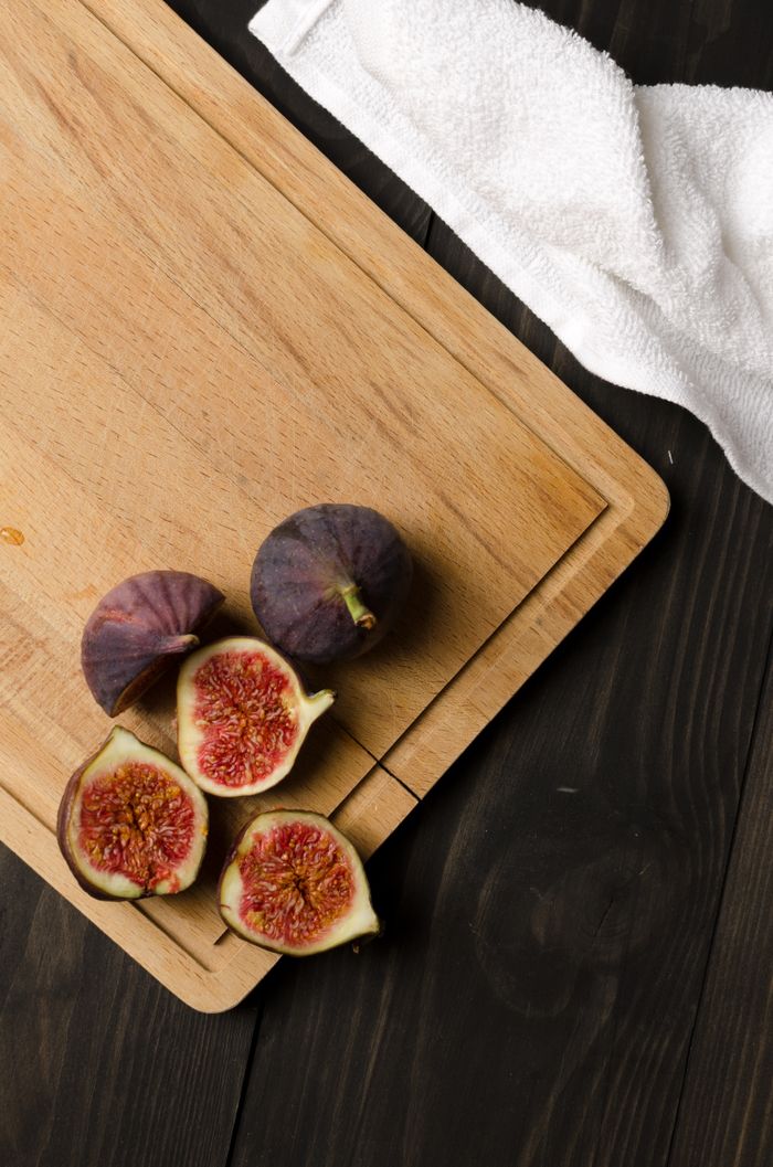 Walnut serving board with fresh figs on a dark table. Photo by Александр Трубицын on Pexels