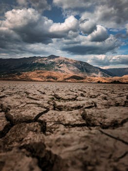 Stunning view of a cracked dry landscape under a cloudy sky near mountains, perfect for nature themes.