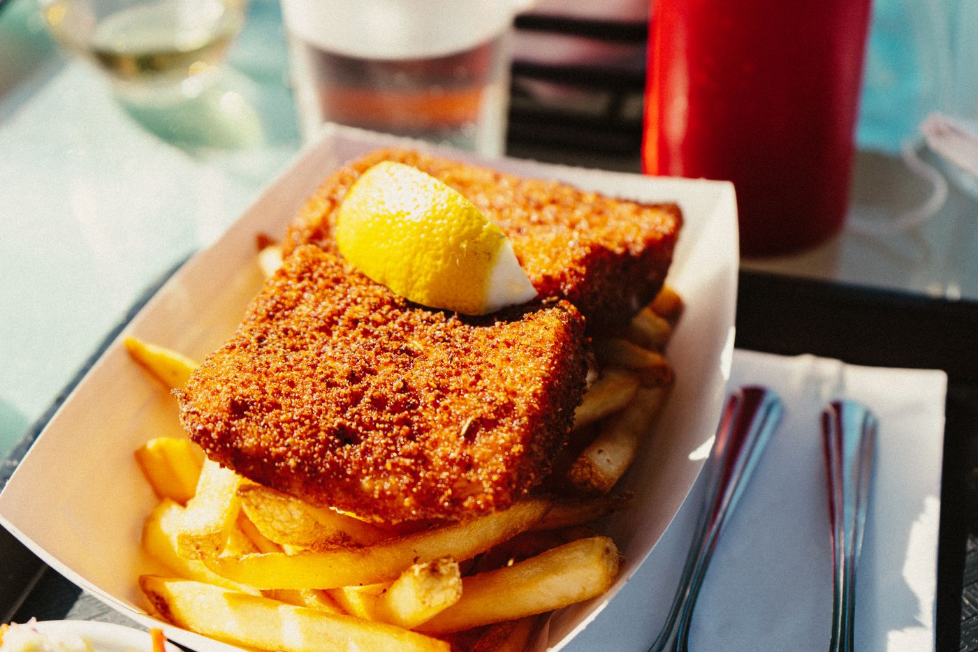 Hand-breaded fried catfish with a lemon wedge and seasoned fries