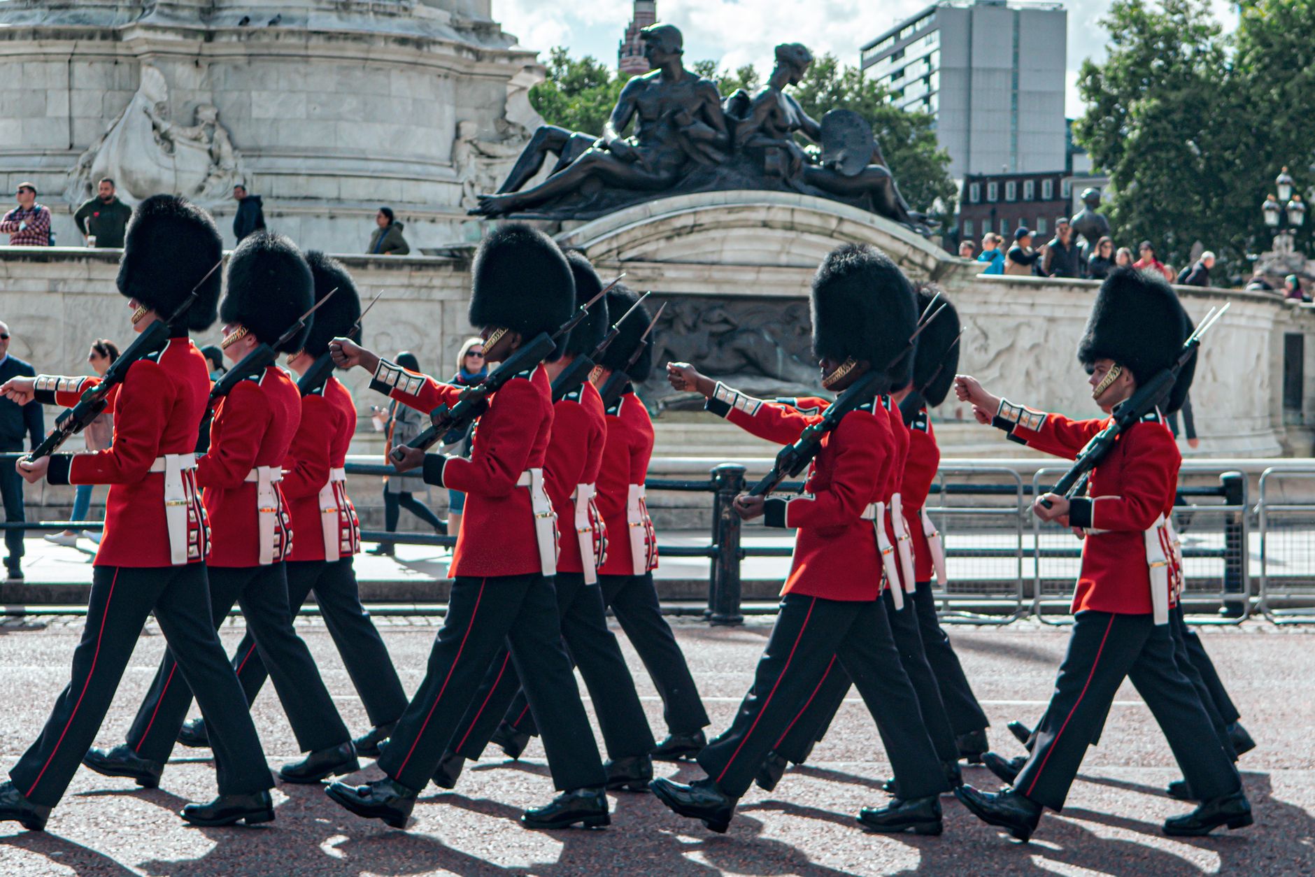 British guards in traditional red uniforms march at Buckingham Palace, showcasing English heritage.