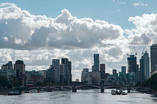 Free Urban skyline featuring a bridge over a river under cloudy skies. Stock Photo