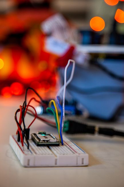 Detailed close-up of electronics breadboard with colorful wires and blurred lights in the background. Detailed close-up of electronics breadboard with colorful wires and blurred lights in the background.