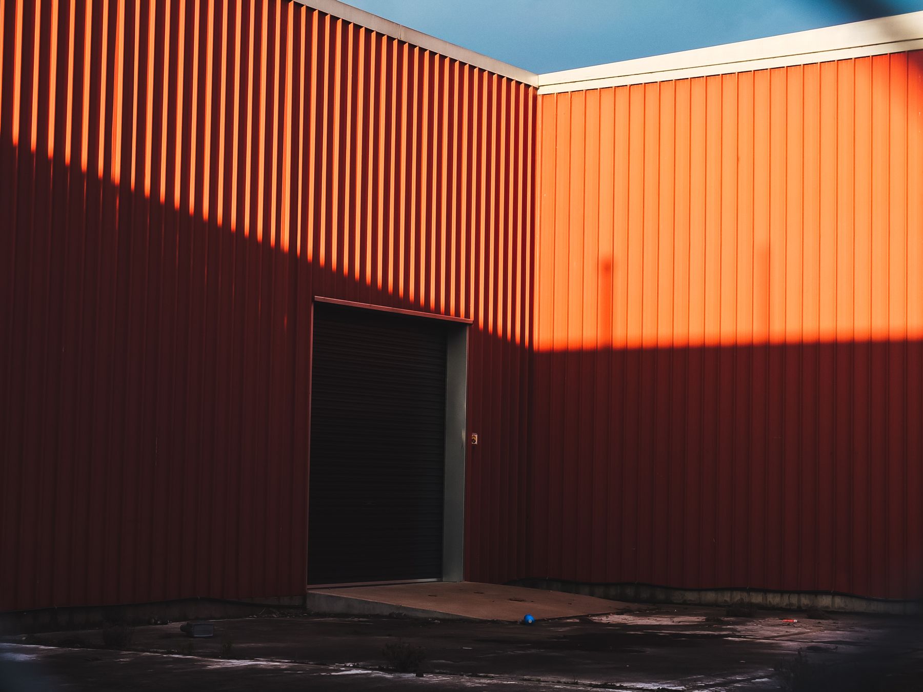 A corrugated warehouse wall lit orange by low evening sun