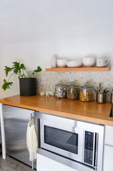Stylish kitchen counter with glass jars and potted plant in a minimalist setting.