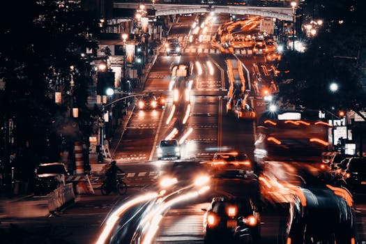 Dynamic city street at night with blurred car lights and bustling traffic, creating a vibrant, urban atmosphere.