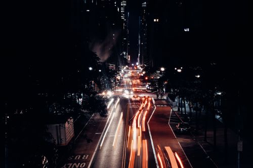 Free Illuminated urban street scene at night with striking light trails from vehicles. Stock Photo