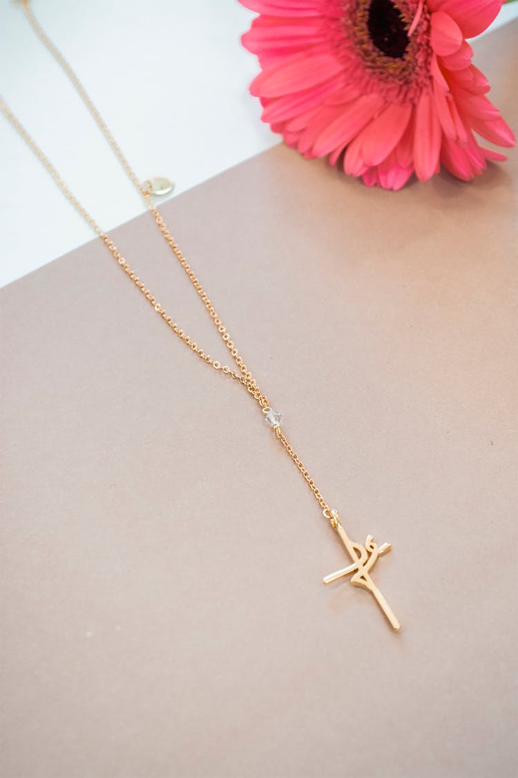 Gold Cross Pendant Necklace On Flat Surface