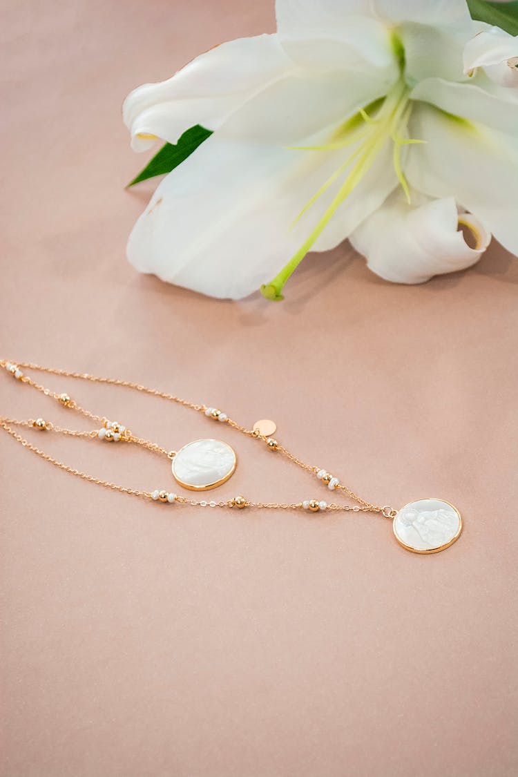 Gold Chain Necklace With Mother Of Pearl Pendant Near White Flower