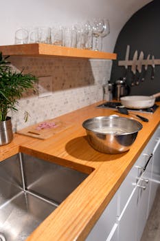 Contemporary New York kitchen featuring a wooden counter, stainless steel sink, and stylish utensils.