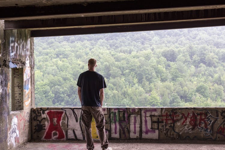 Man In Black Shirt And Khaki Pants Standing Inside The Abandoned Building 