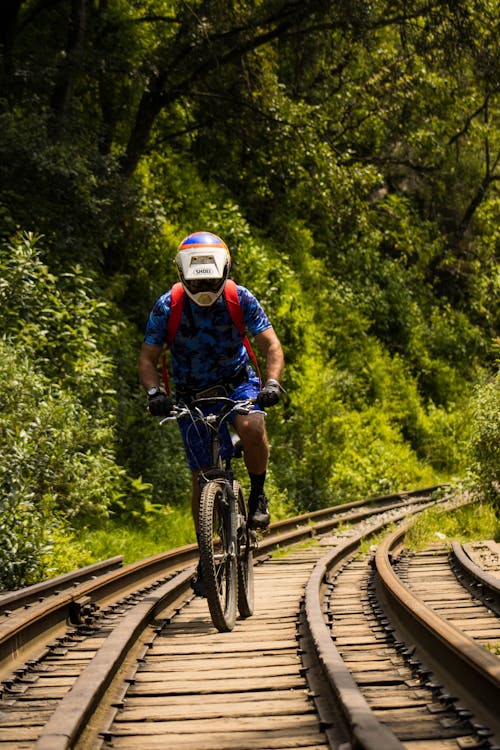 Man Cycling on a Railway Track 